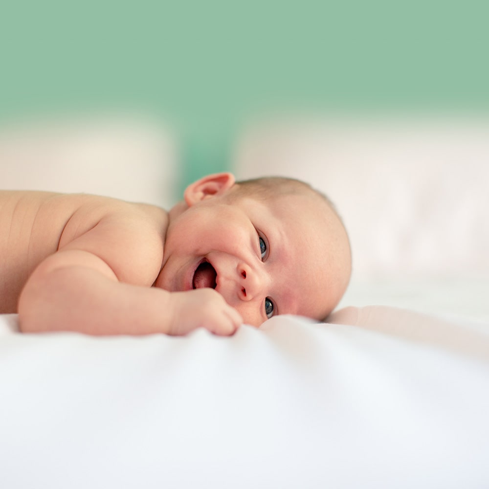 smiling baby lying on a bed